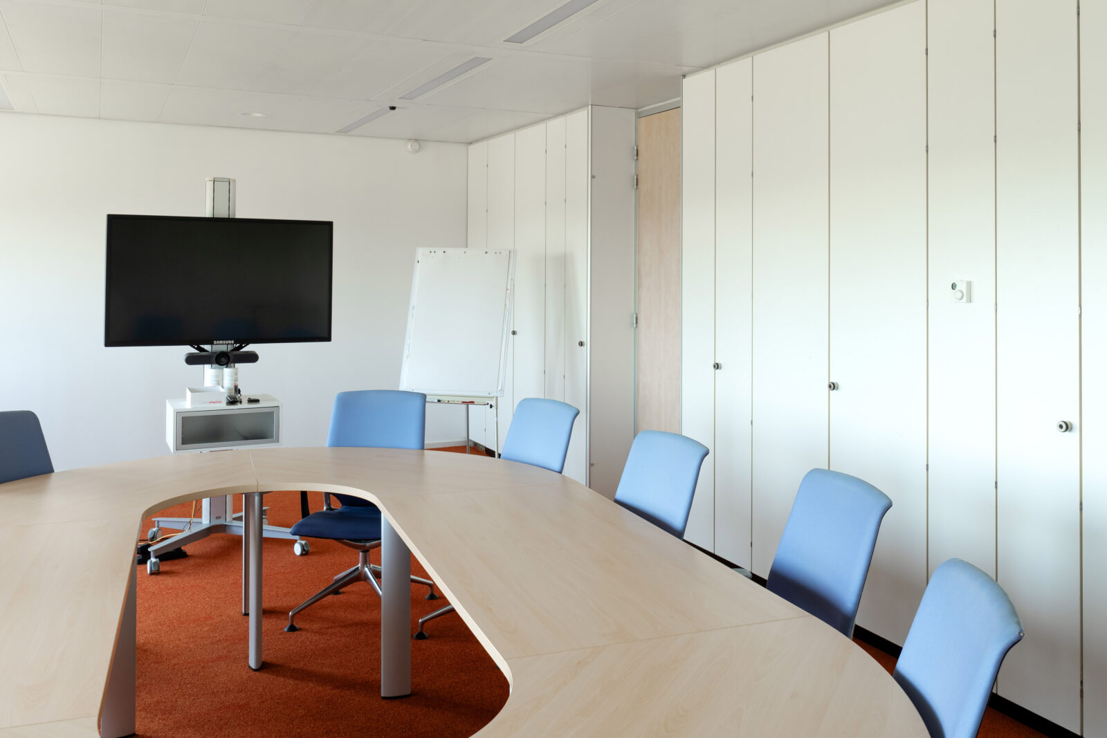 Vergaderruimte met ovale tafel, scherm en flip-over voor presentaties