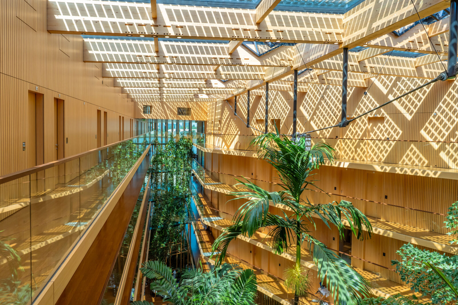 Atrium van hotel Jakarta met glazen dak, houten balken en hangende beplanting met gebouwbeheersystemen