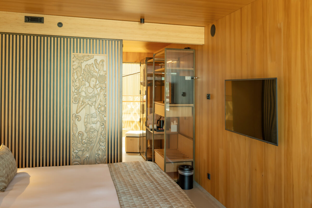 Hotelkamer met Balinese houtsnijwerk deur en televisie met thermostaat voor klimaatregeling