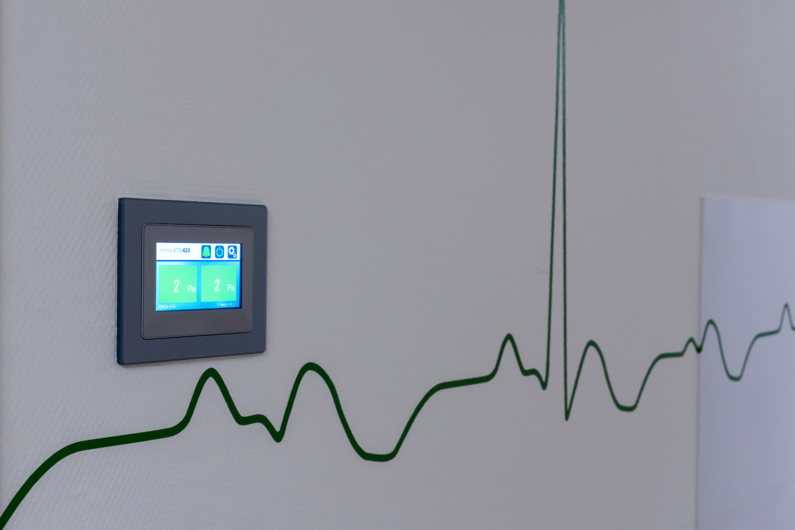 Detail van drukmeetpaneel met hartslaglijn-motief op de wand